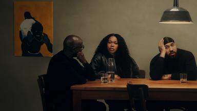 Rapper OG Keemo (rechts) sitzt mit seiner Schwester, Iman Rahel Martin (Mitte) und seinem Vater (links), Mustafa Martin, an einem Tisch. OG Keemo und seine Schwester schauen frontal in die Kamera, sein Vater schaut seine beiden Kinder an.