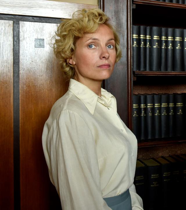 Margarete Oelkers (Nadja Uhl) verlangt von Amtsarzt Dr. Ahrens (Rudolf Kowalski) eine Bescheinigung, dass sie nie schizophren war. Sie wirft ihm vor, sie ohne Grund in die Klinik Wehnen eingewiesen zu haben. "Ich werde nicht schweigen": Margarete Oelkers (Nadja Uhl) und Amtsarzt Dr. Ahrens (Rudolf Kowalski) stehen vor einem Bücherregal. Margarete blickt in die Ferne, Ahrens blickt sie provozierend an.