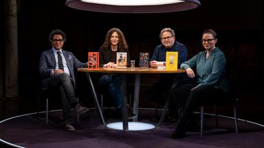Ijoma Mangold, Sandra Richter, Wolfram Eilenberger und Gastgeberin Thea Dorn sitzen in einem dunklen Raum an einem Tisch und blicken in die Kamera. Sie werden von oben von einer Lampe beleuchtet.