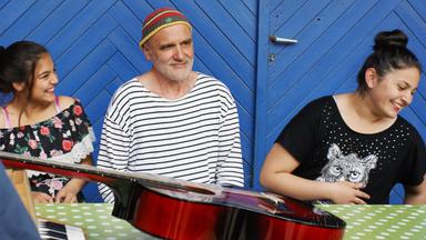 Ein Mann mit Bart sitzt zwischen zwei Mädchen.