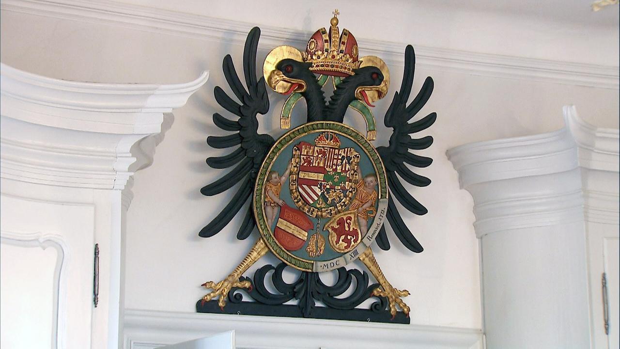 Bunt bemalte Wappen auf einem schwarzem Doppeladler an einer weissen Wand angebracht