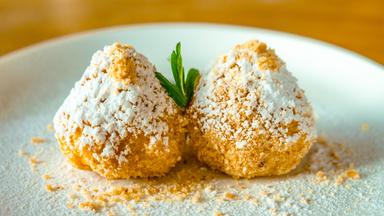 Zwei Topfenknödel mit Puderzucker bestreut auf einem Teller