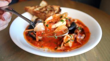 Eine Fischsuppe in einer weißen Schüssel mit Petersilie garniert.