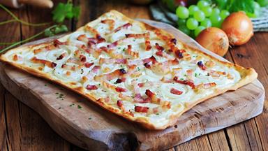 Ein Flammkuchen auf einem Holzbrett
