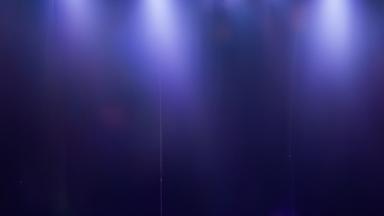 Spotlights strahlen in einem dunklen Raum auf eine Bühne 