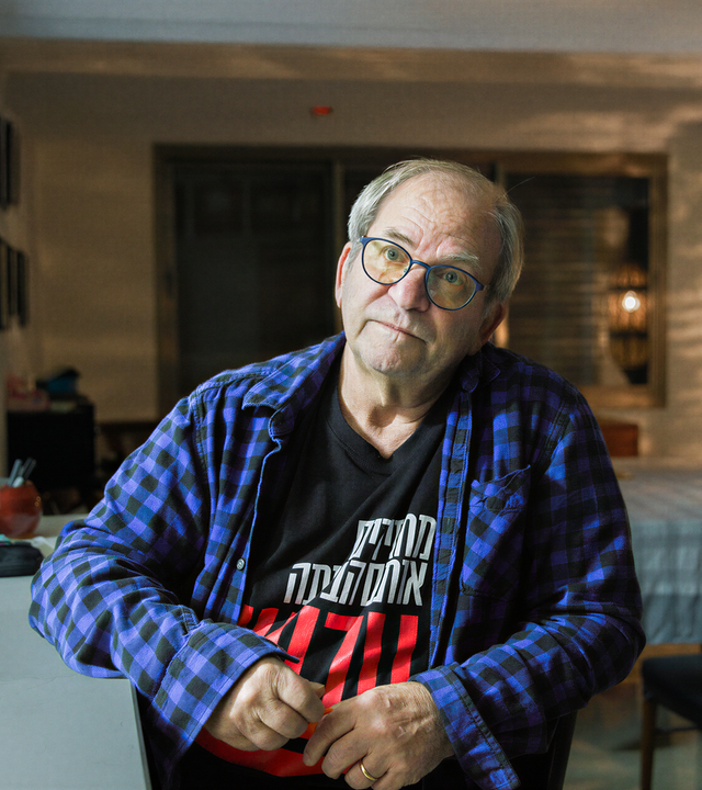 Mann sitzt seitlich an einem Schreibtisch mit einem geöffneten Laptop.