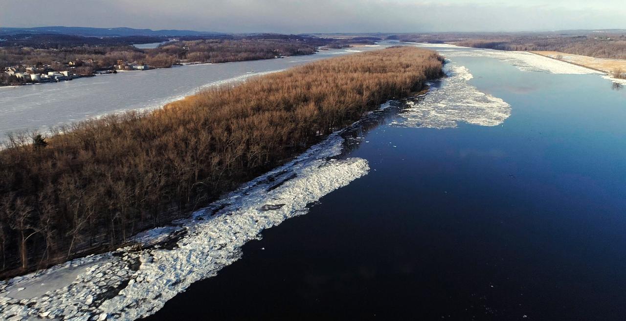 Breiter Fluss mit Landzunge in der Mitte im Winter