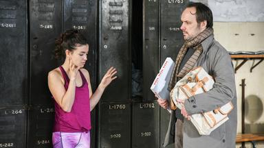 "Hüftkreisen mit Nancy": Nancy (Helen Woigk) und Max (Felix Knopp) stehen vor Schließfächern im Fitnessstudio, sie in Sportklamotten, er im Alltags-Outfit und mit einem Pizzakarton und seiner Aktentasche unter dem Arm.