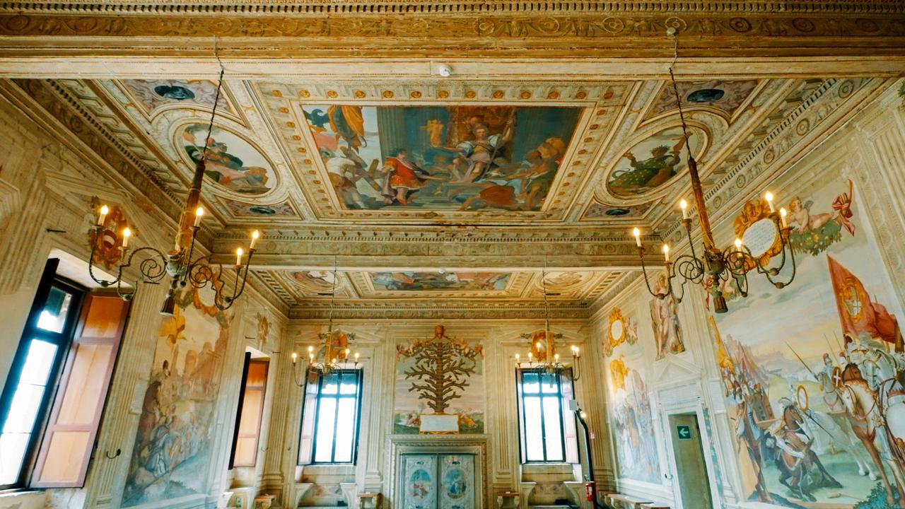 Innenaufnahme des prächtig bemalten Saals im Castello del Catajo, mit Wand- und Deckenfresken sowie prunkvollen Kronleuchtern.