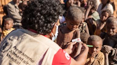 Eine Frau misst den Armumfang eines Kindes. 