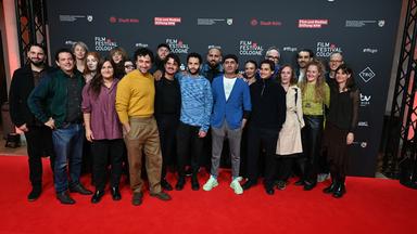 Gruppenbild zahlreicher Männer und Frauen auf einem roter Teppich.