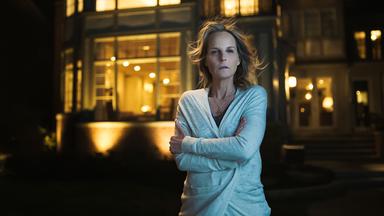 Eine Frau vor einem großen, luxuriösen Haus.