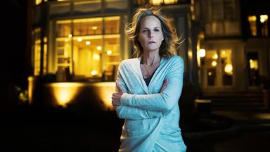 Eine Frau vor einem großen, luxuriösen Haus.