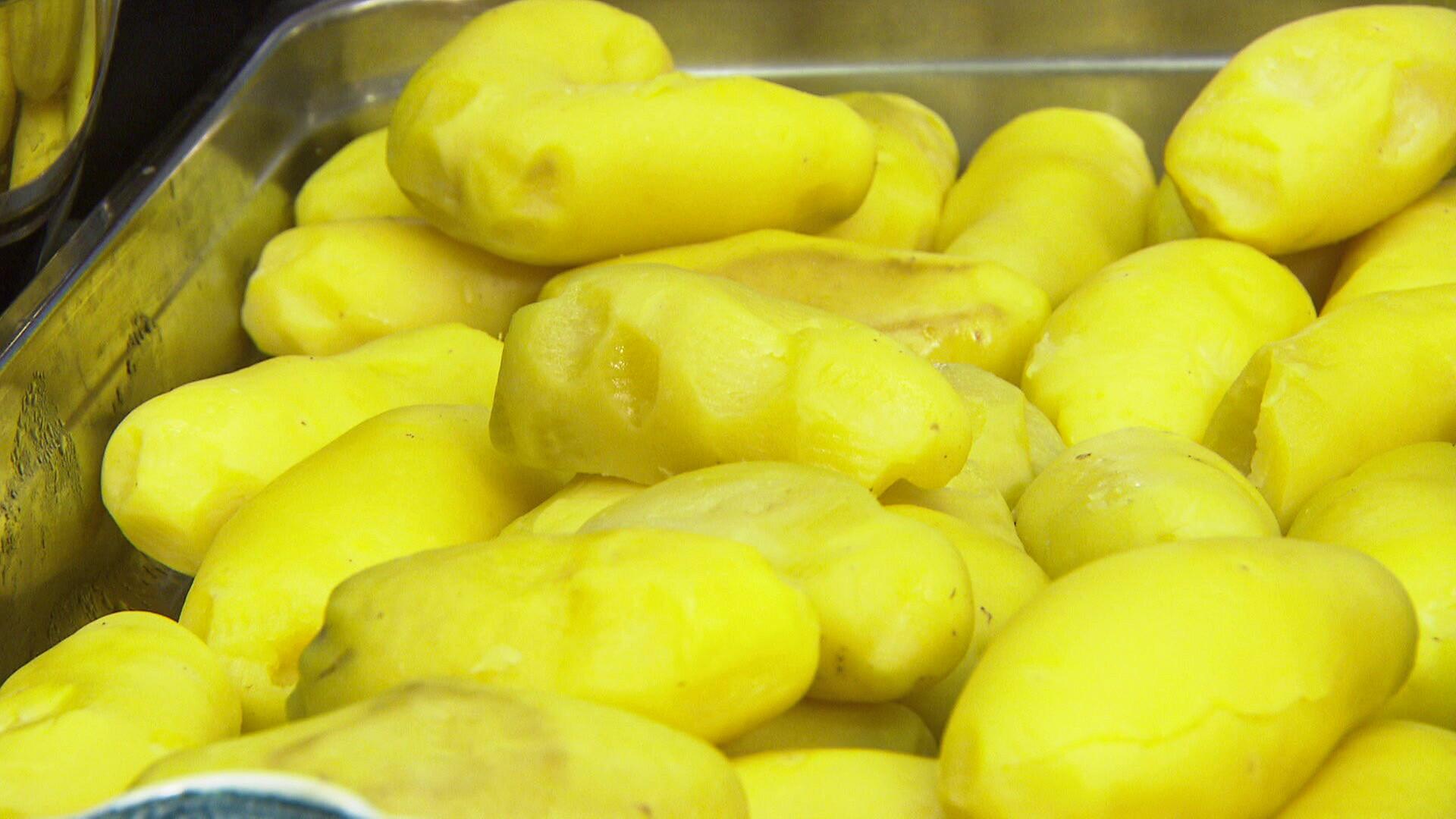Geschälte, gelbe Kartoffeln liegen in einer Metallschale bereit zur weiteren Verarbeitung.