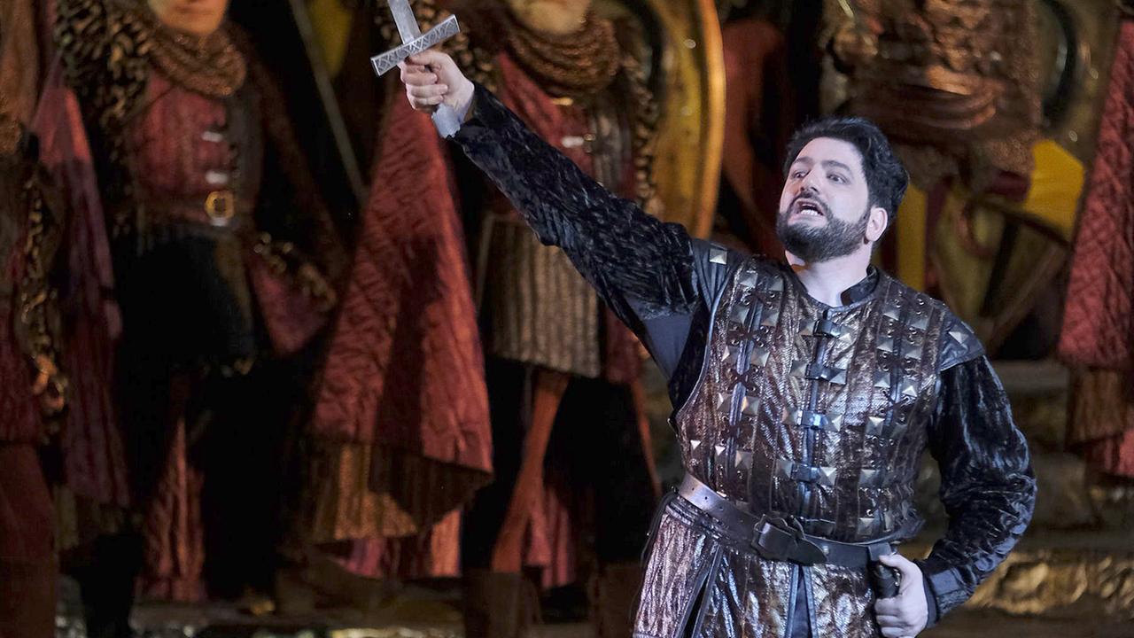 Blick auf die Bühne von “Il Trovatore” in der Arena di Verona. Yusif Eyvazov streckt seine,mit einem Schwert bewaffnete, rechte Hand in die Luft. Die linke Hand umfasst seine leere Schwerthalterung.  