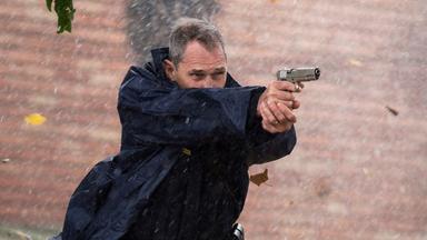 Sheriff Dixon (Ben Cross) steht mit erhobener Waffe im Freien und zielt auf jemanden außerhalb des Bildes. Um ihn herum tobt der Sturm.