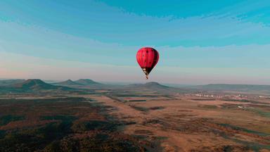 Ein Heißluftballon schwebt über eine karge Landschaft