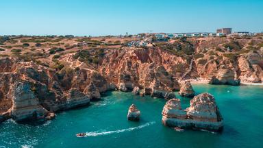 Atemberaubendes Luftbild der felsigen Küste in Lagos, in der Algarve-Region von Portugal, mit klarem blauen Meer.