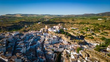 Luftaufnahme von Setenil de las Bodegas in Andalusien. Weiße Häuser liegen dicht zwischen den Felsen und ziehen sich durch das Tal.