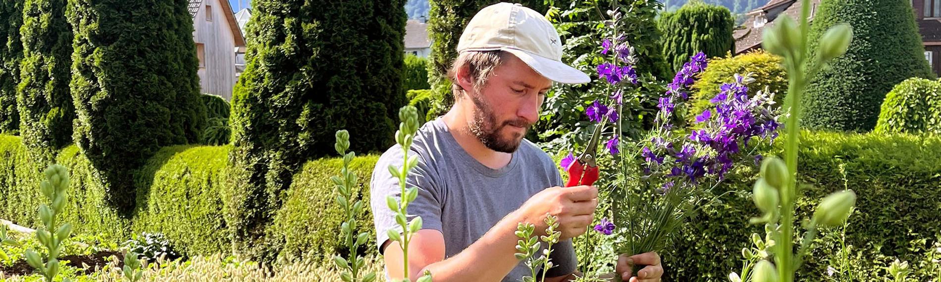 Sebastian Geiger in einem Garten und steckt Blumen zusammen