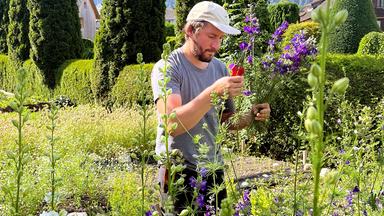 Sebastian Geiger in einem Garten und steckt Blumen zusammen