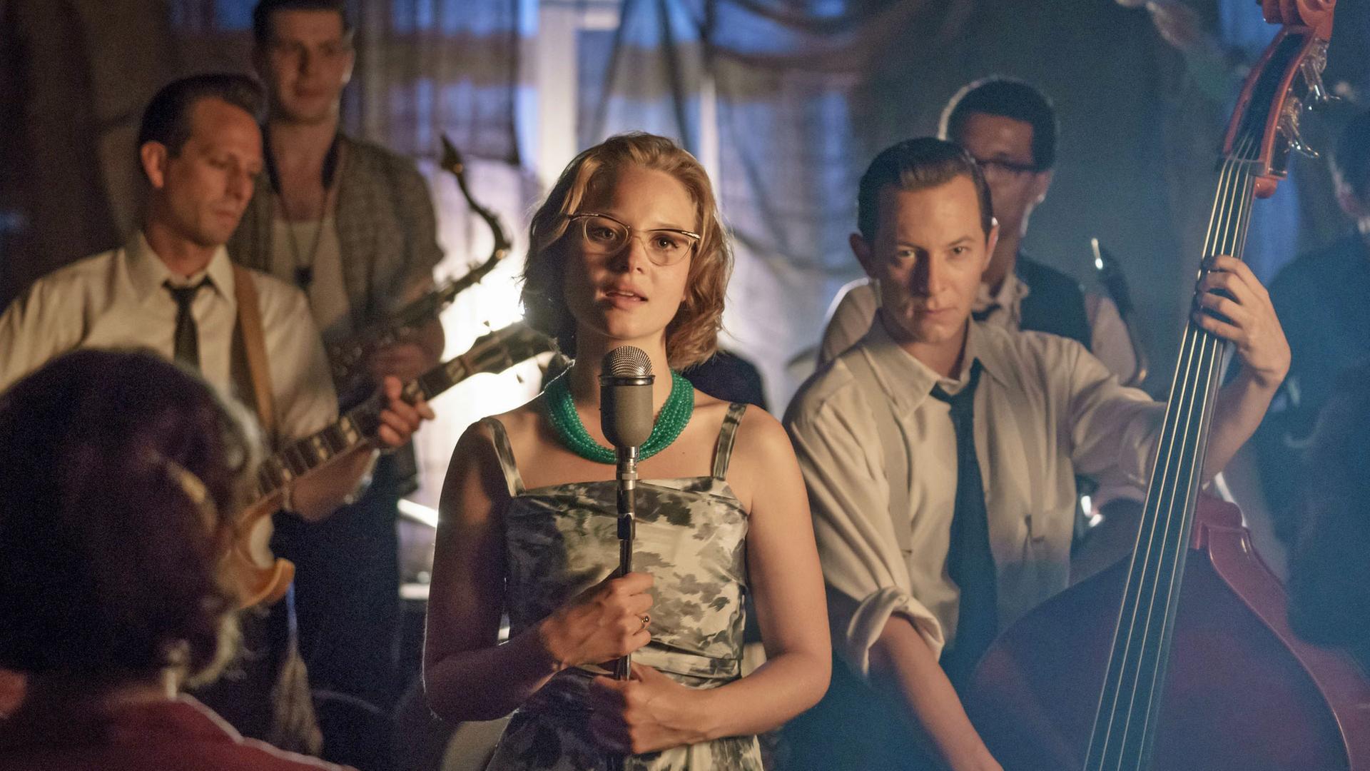 Monika Schöllack (Sonja Gerhardt) steht auf einer Bühne und singt, während Freddy Donath (Trystan Pütter) etwas hinter ihr Kontrabass spielt. Weitere Musiker stehen hinter den beiden.