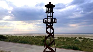"Inselträume: Die Ostfriesischen Inseln - Welten im Watt": Ein Leuchtturm auf einer Ostfriesischen Insel. Im Hintergrund das Meer.