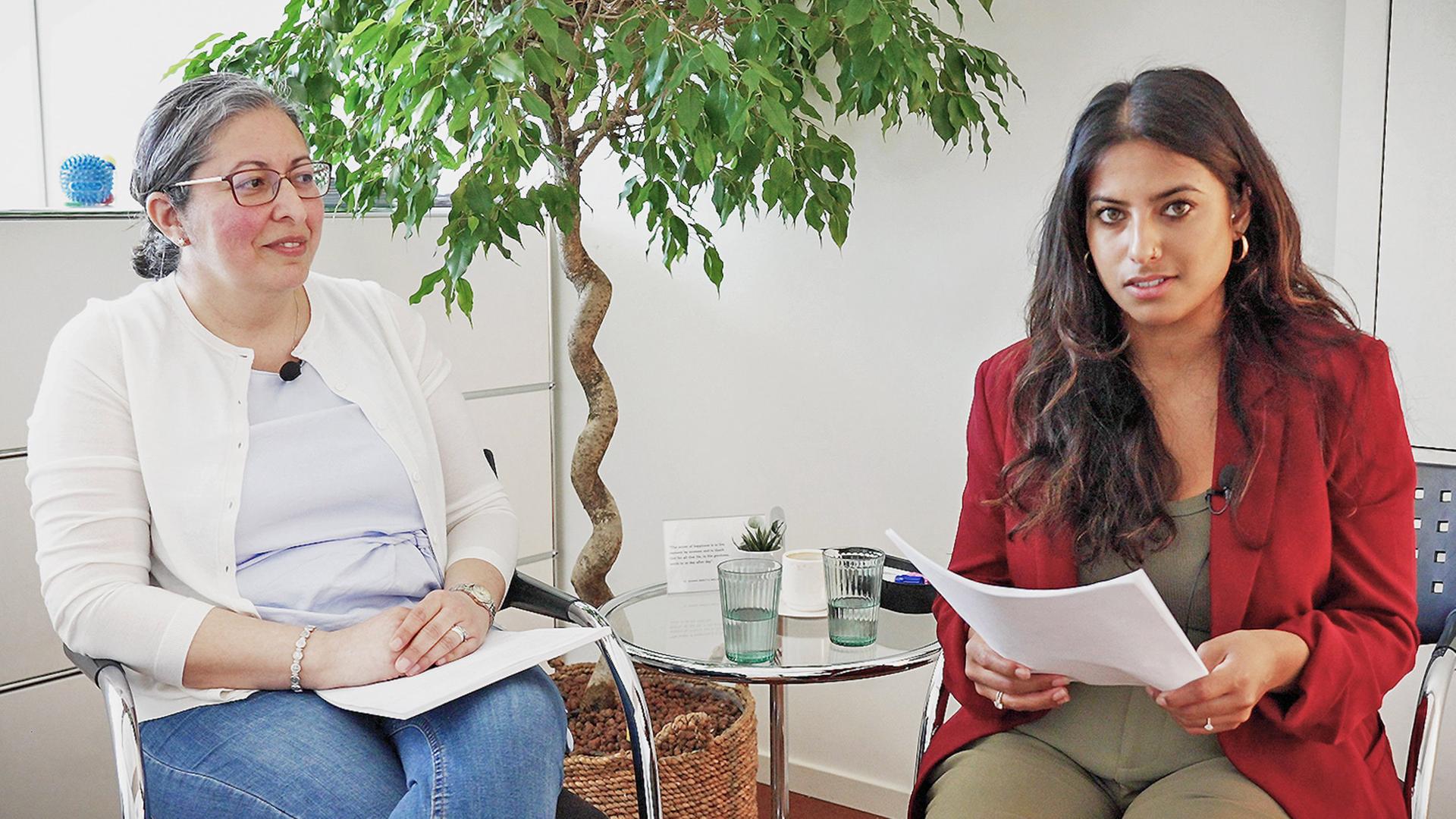 Zwei Frauen sitzen neben einem Glastisch