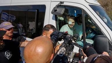 Ein weißer Transporter, in dem mehrere Männer sitzen und herausschauen wird von Kameraleuten und Fotografen belagert.