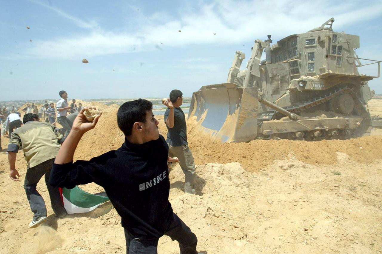 Palästinensische Jugendliche werfen Steine auf einen israelischen Bagger in Beit-Lahya.