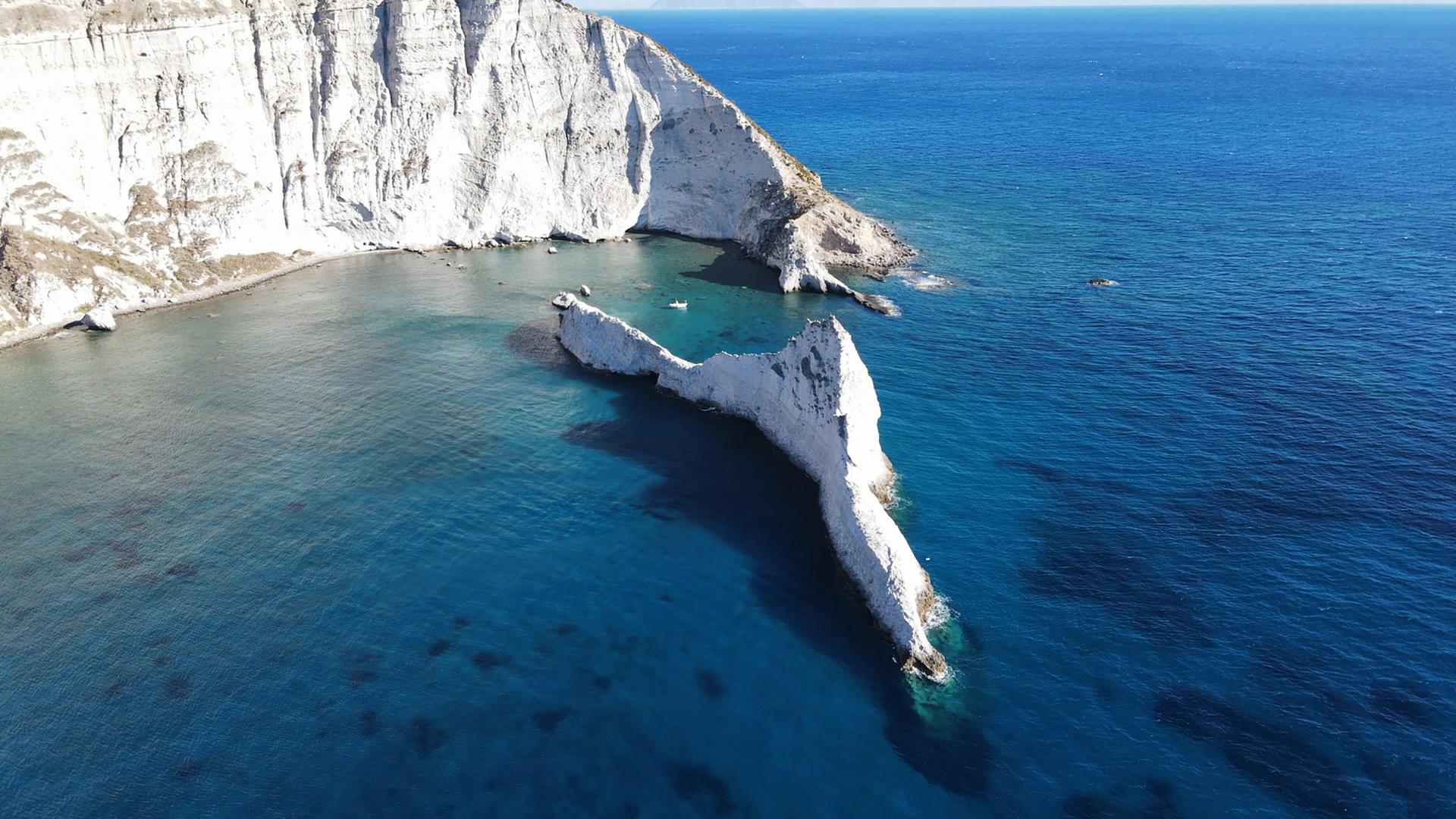 Luftaufnahme einer weißen Steilküste mit kantigen Felsinformationen in tiefblauem Meer