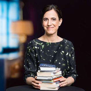 Lächelnde dunkelhaarige Frau mit Bücherstapel