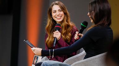 Zwei junge Frauen sitzen nebeneinander und sprechen in Mikrofone.