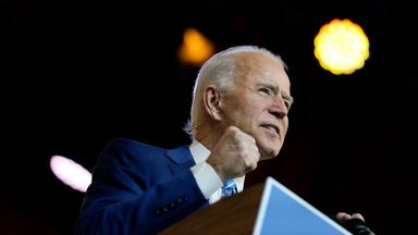 Ein älterer Mann steht an einem Rednerpult auf einer Bühne und ballt seine Hand zu einer Faust.