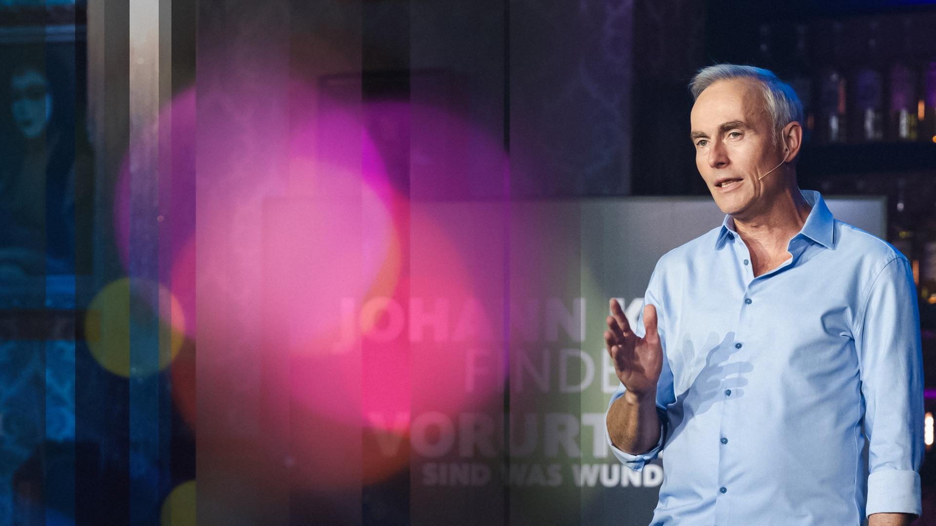 Johann König im hellblauen Hemd beim Moderieren.