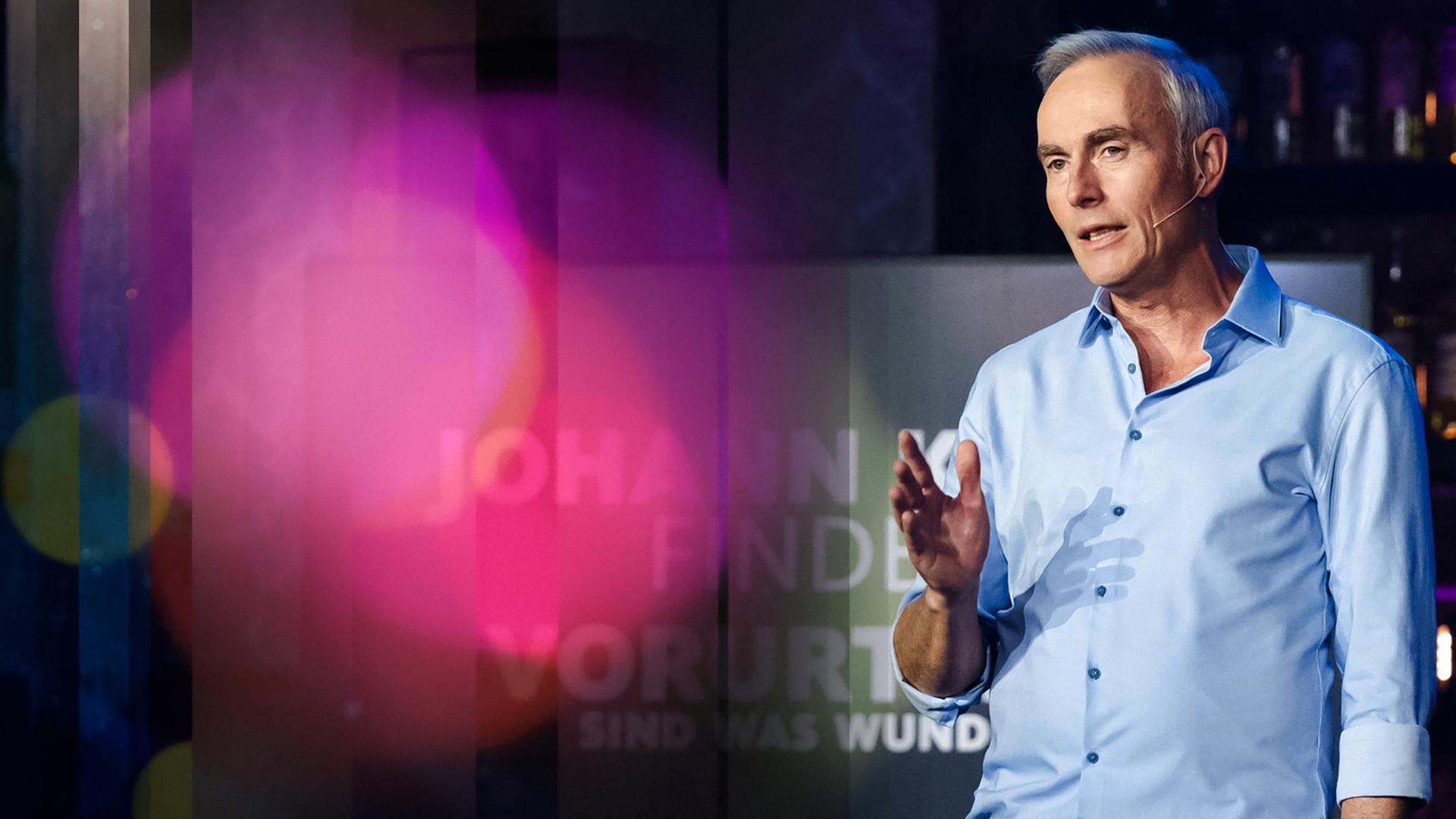 Johann König im hellblauen Hemd beim Moderieren.