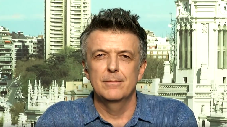 Ein Mann mit kurzen grauen Haaren blickt in die Kamera, hinter ihm sind städtische Gebäude zu sehen.