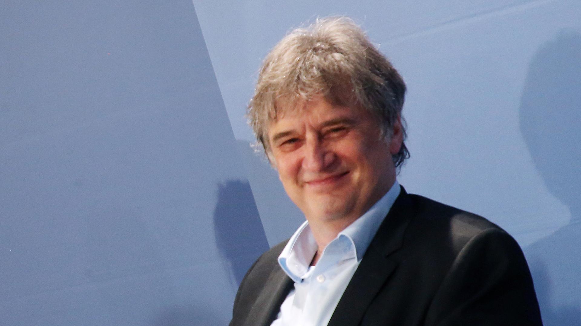 Ein Mann im Anzug lächelt in die Kamera.