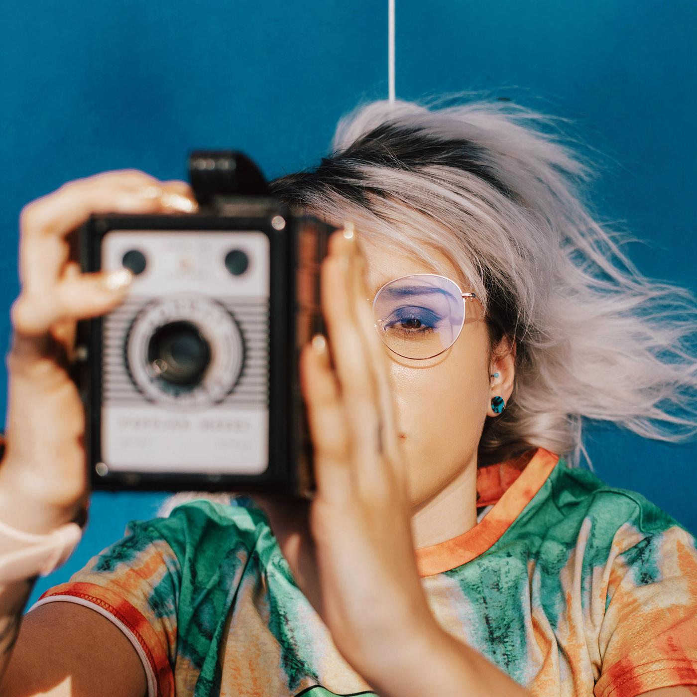 Eine junge Frau macht ein Foto mit einer analogen Kamera.