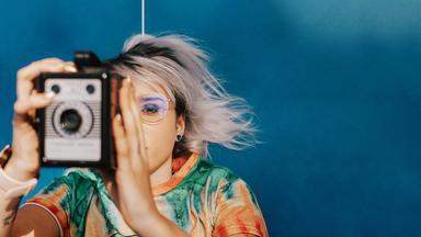 Eine junge Frau macht ein Foto mit einer analogen Kamera.