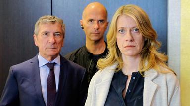 Davids Chef Hagedorn (Rudolf Kowalski, li.) und Michael (Christoph Maria Herbst) sind Claire (Caroline Peters) keine Hilfe bei ihren Nachforschungen über das Doppelleben ihres Mannes.