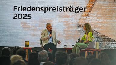 Eine Frau und ein Mann sitzen auf einer Bühne und diskutieren.