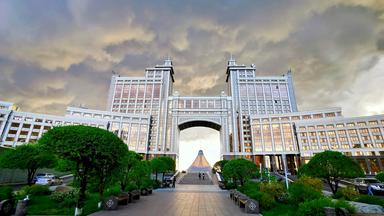 Ansicht eines großen, imposanten Gebäudes mit einem Durchgang an einem großen Platz.