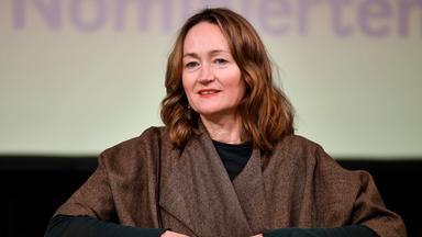 Porträtfoto einer Frau mittleren Alters mit langen rötlichen Haaren.