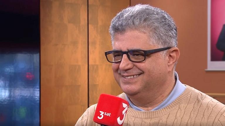 Kaveh Farnam spricht lachend in ein 3sat-Mikrofon.