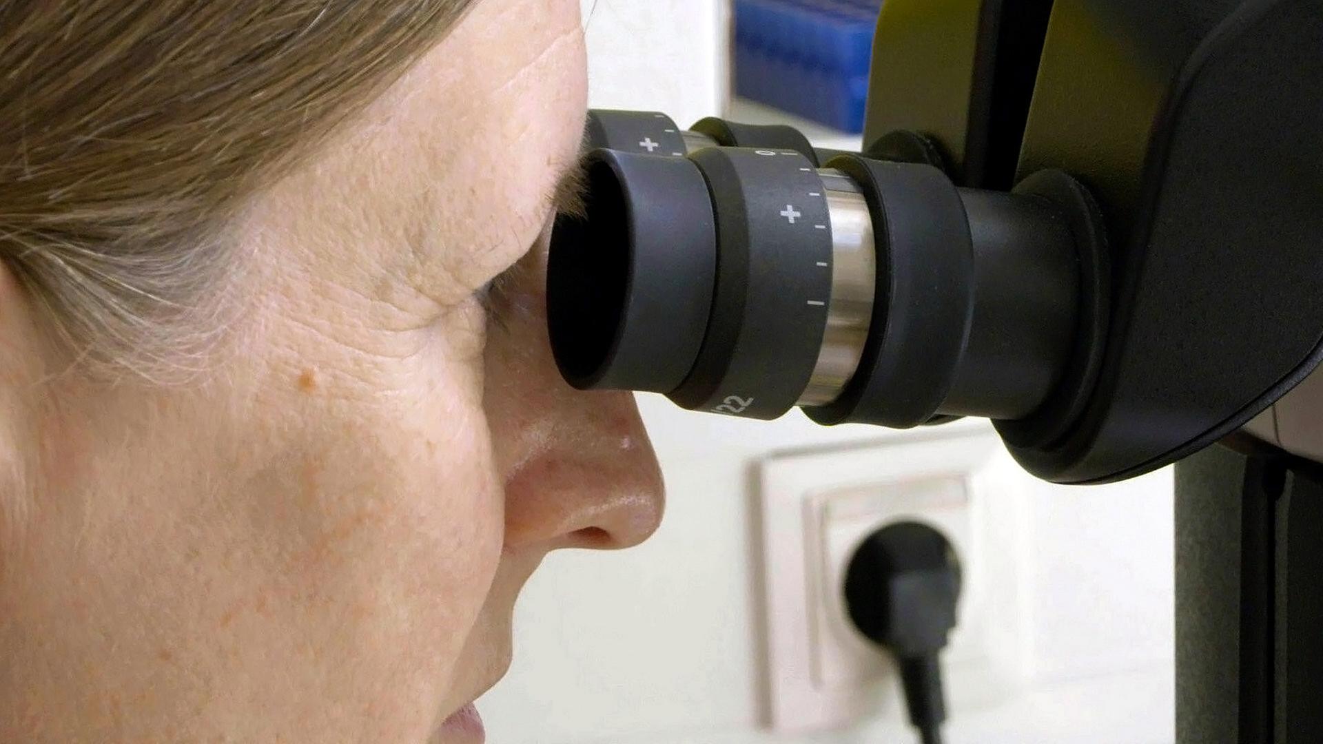 Eine Wissenschaftlerin beim Blick ins Mikroskop