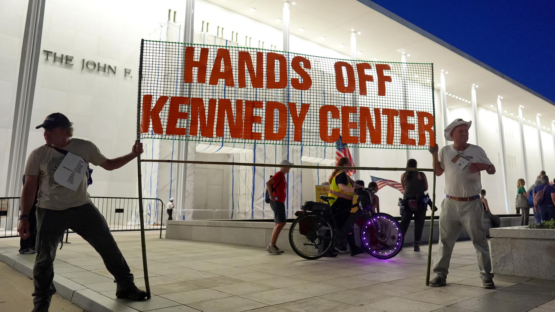 Menschen halten Banner mit Schriftzug: "Hands Off Kennedy Center" 