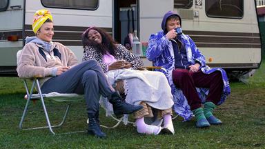 Drei junge Menschen auf Campingstühlen vor einem Wohnwagen.