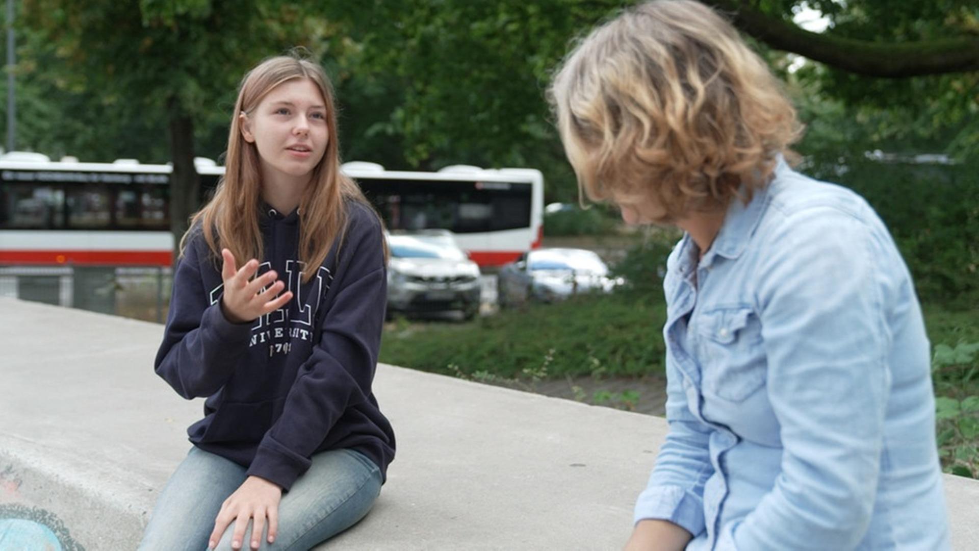 Zwei Jugendliche sitzen auf einer Mauer