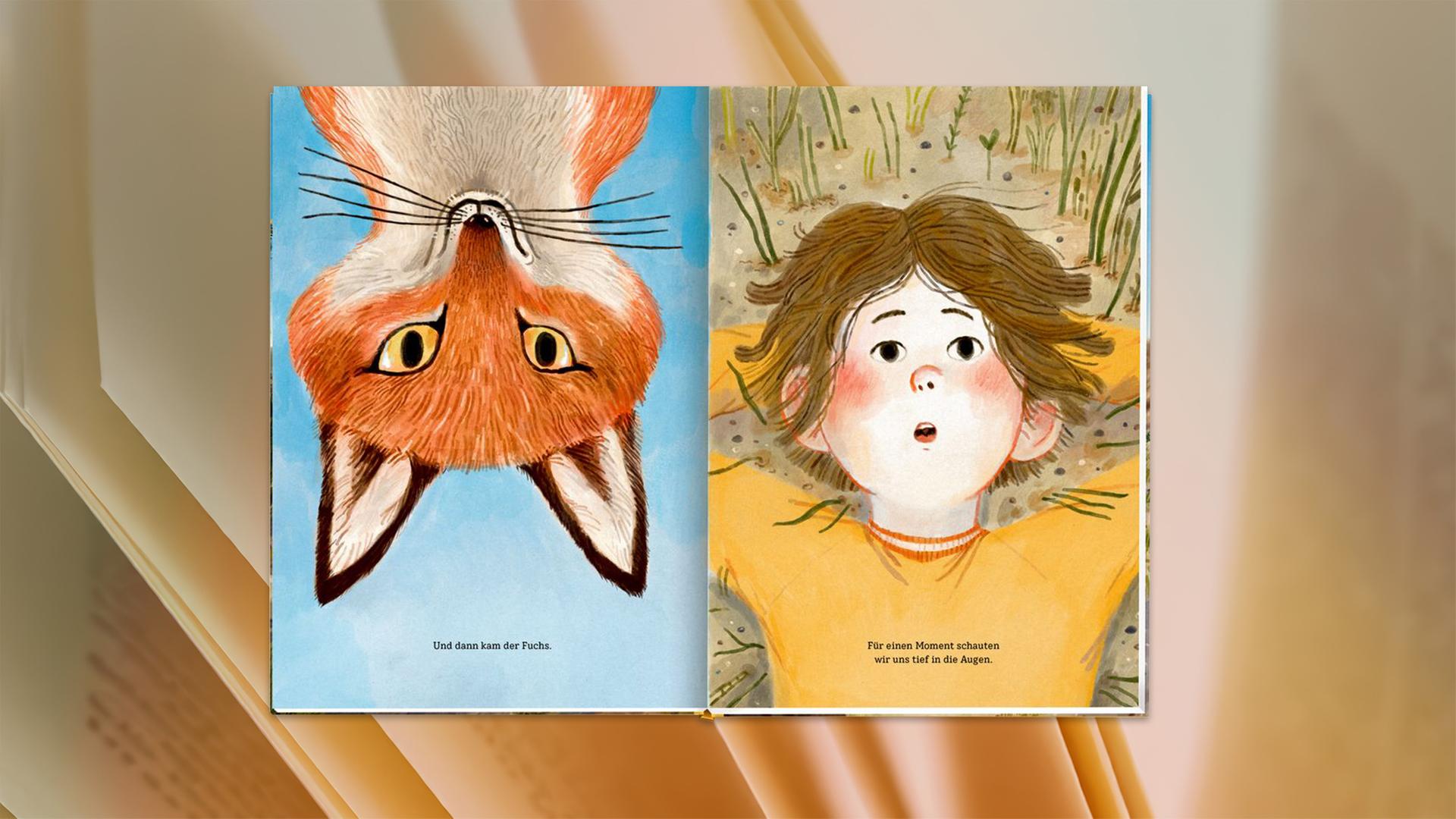 Auf den aufgeschlagenen Seiten eines Kinderbuches sieht man einen auf dem Kopf stehenden Fuchs und daneben einen Jungen, der im Gras liegt.